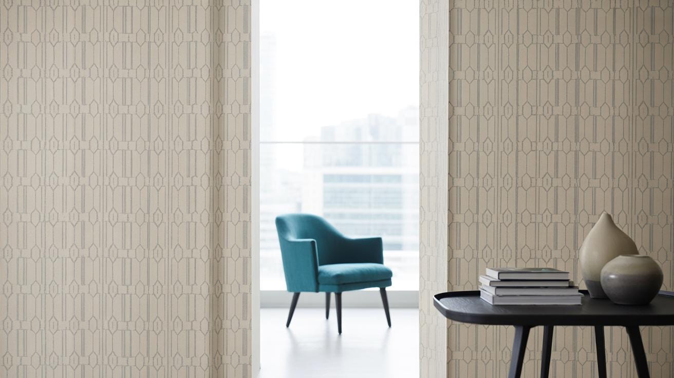 A modern room with patterned beige walls, a teal armchair near a large window, and a black table holding books and decorative vases in the foreground. City buildings are visible through the window.