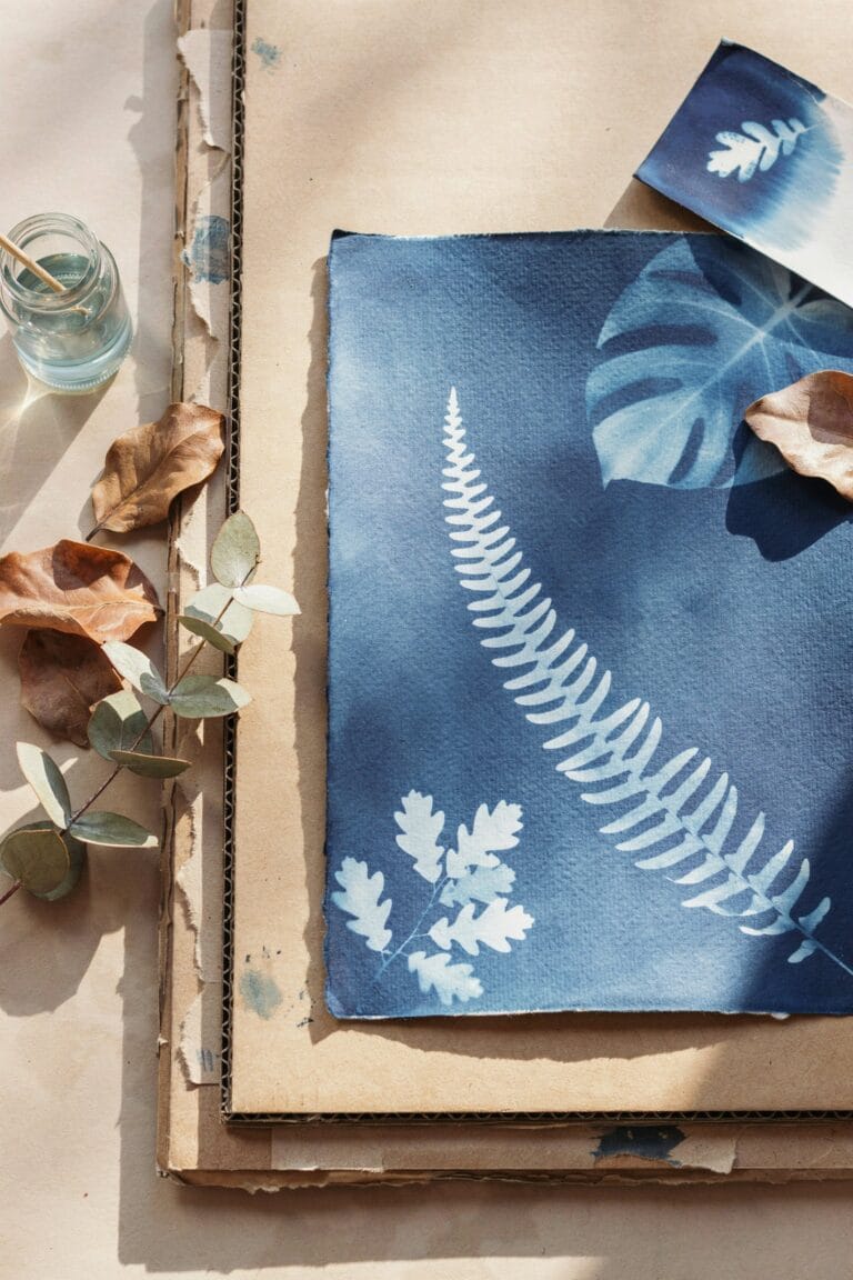 Cyanotype sun print on cardboard relief sculpture, deep blue tones with botanical silhouettes
